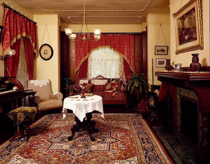 وجود پرده قرمز میز چوبی و رومیزی سفید وصندلی و شومینه و فرش در تصویر 789798
